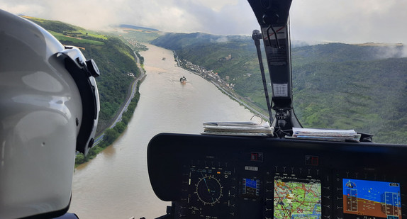 Innenansicht des Cockpits eines Polizeihubschraubers, der einen Fluss überfliegt.