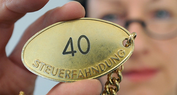 Eine Mitarbeiterin der Steuerfahndung hält ihre Fahndermarke in der Hand. (Foto: © dpa)