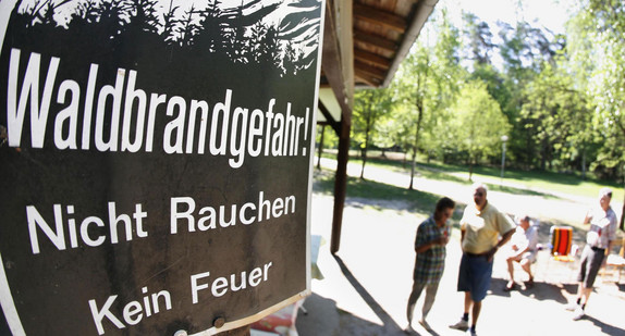 Ein Schild an einer Schutzhütte im Wald weist auf Waldbrandgefahr hin.