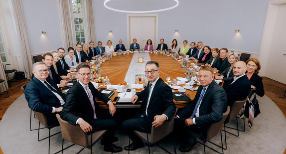 Beschreibung des Bildes: Blick in den Kabinettssaal in der Villa Reitzenstein in Stuttgart. Am großen ovalen Tisch sitzen Ministerpräsident Cem Özdemir und die Mitglieder der Landesregierung.