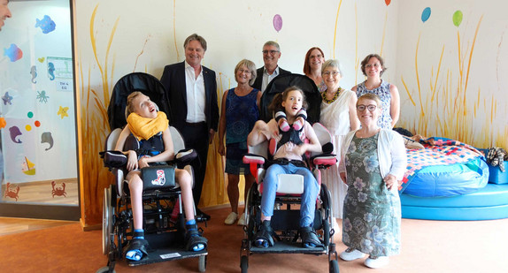 Gruppenfoto: Minister Manne Lucha und Simone Fischer zusammen mit Karin Eckstein, Gründerin der Familienherberge und Mitarbeitende, die Landtagsabgeordnete Stefanie Seemann und Illingens Bürgermeister Armin Pioch sowie Emma und Marius.