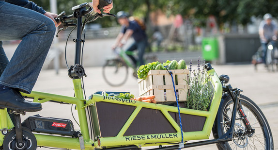 Ein Mann transportiert Lebensmittel auf einem, mit einem Elektromotor unterstützten, Lastenfahrrad.