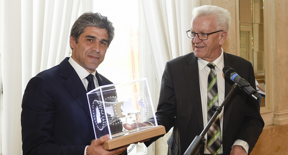 Ministerpräsident Winfried Kretschmann (r.) übergibt Staatssekretär Alan Christian Rizzi (l.), Lombardei, einen Kubus (Bild: Staatsministerium Baden-Württemberg)