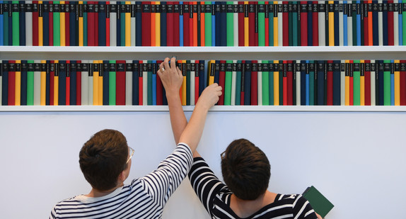 Zwei Frauen stellen auf der Frankfurter Buchmesse am Stand des Diogenes Verlags Zürich Bücher in ein Regal. (Bild: © dpa)