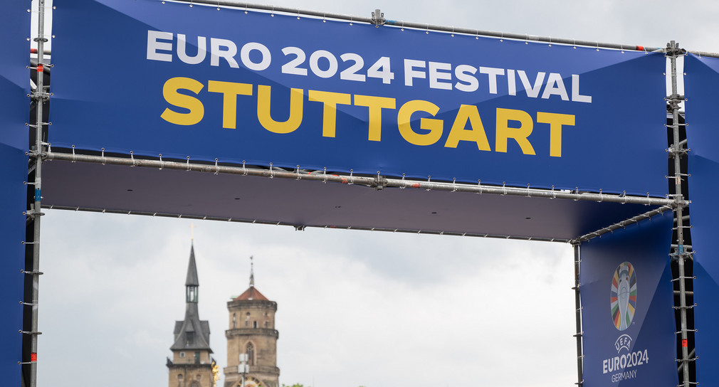 Die Türme der Stiftskirche ist beim Aufbau des Public Viewing für die Fußball-Europameisterschaft in Deutschland auf dem Stuttgarter Schlossplatz hinter einem Eingang zur Fanmeile zu sehen.