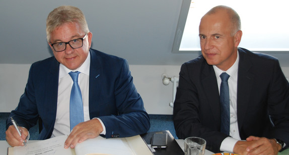 Justizminister Guido Wolf (l.) trägt sich in das Gästebuch der JVA Bruchsal ein. Rechts neben dem Minister sitzt Martin Finckh, Leiter der Abteilung Justizvollzug des Ministeriums der Justiz und für Europa Baden-Württemberg.