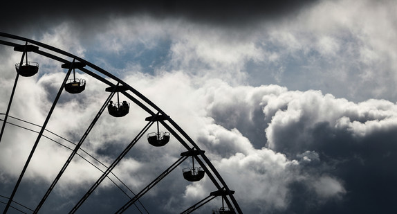 Dunkle Wolken ziehen beim 174. Cannstatter Volksfest hinter einem Riesenrad vorbei. (Bild: picture alliance/Christoph Schmidt/dpa)