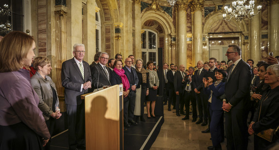 Ministerpräsident Winfried Kretschmann (Dritter von links) spricht zu den Gästen, neben ihm stehen die Mitglieder der Landesregierung.