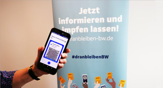 Hand hält digitales Impfzertifikat auf Handy in Kamera