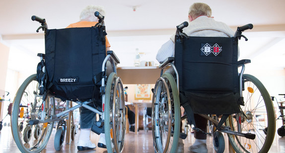 Zwei pflegebedürftige Frauen sitzen in einem Pflegeheim in ihren Rollstühlen nebeneinander. (Foto: © dpa)