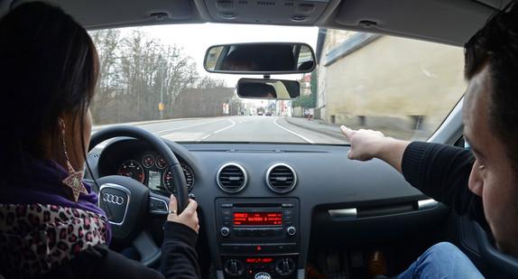 Eine Fahrschülerin sitzt in einem Fahrschulauto neben ihrem Fahrlehrer (Bild: © dpa). 