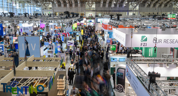 Besucher gehen auf der Hannover Messe durch einen Flur in einer Halle (Bild: picture alliance/Christophe Gateau/dpa)