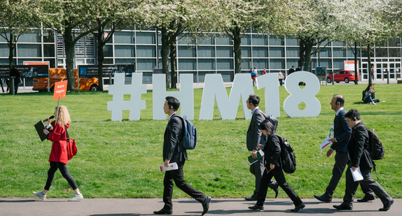 Hannover: Eine geführte Tour geht an dem Schriftzug «#HM18» auf der Hannover Messe vorbei. (Foto: © dpa)