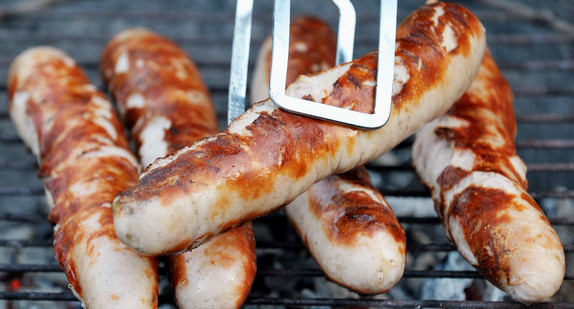 Bratwürste liegen auf einem Holzkohlegrill (Bild: © dpa).