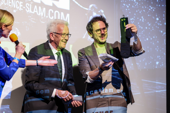 Ministerpräsident Winfried Kretschmann (links) überreicht Moderator Rainer Holl, Science Slam, (rechts) „The Länd-Socken“ in der Alten Feuerwache in Mannheim.