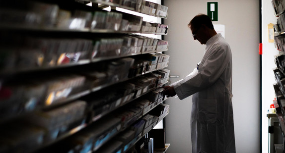 Ein Apotheker der Universitätsklinik Freiburg steht in der Apotheke des Klinikums vor einem Regal. (Bild: picture alliance/Philipp von Ditfurth/dpa)