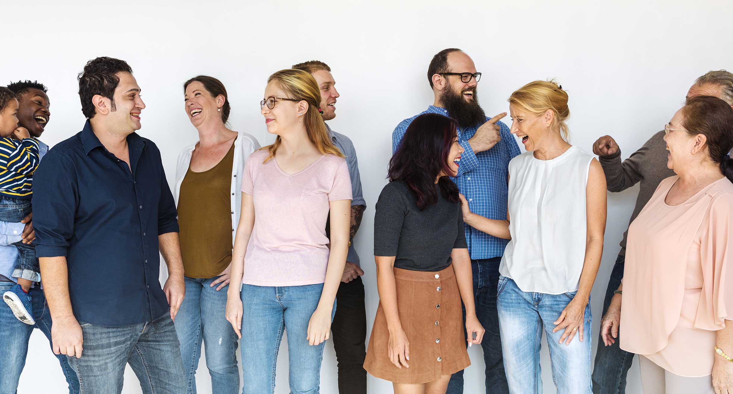 Eine bunt gemischte Gruppe Menschen steht vor einer Wand.']