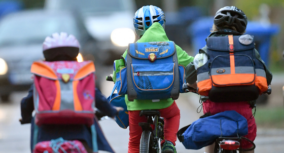 Kinder sind auf einer Straße mit dem Fahrrad unterwegs zur Schule. (Foto: © dpa)