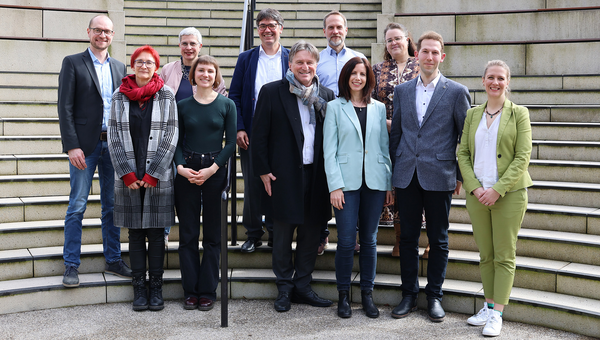 Gruppenbild auf Treppe vor Landtag Baden-Württemberg: Sozialminister Manne Lucha mit Vertreterinnen und Vertretern der sechs „Housing First“-Modellprojekte.