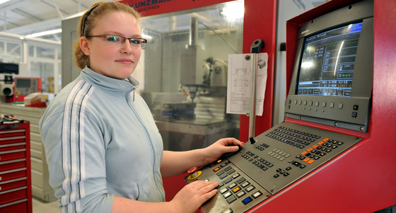 Eine Auszubildende steht am Schaltpult einer computergesteuerten Fräsenmaschine (Symbolbild, © dpa).