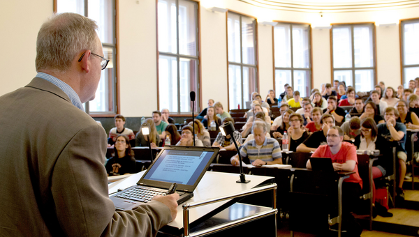 Ein Professor hält in einem Hörsaal vor Studierenden eine Vorlesung.