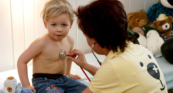 Eine Kinderärztin untersucht einen kleinen Jungen mit einem Stethoskop (Bild: © dpa).